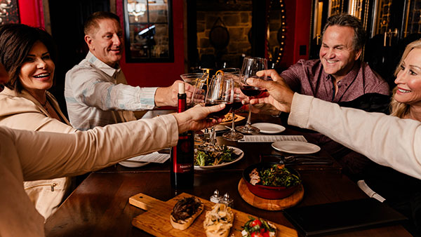 Guests toasting red wine and enjoying gourmet dishes in the elegant ambiance of The Bistro at Gervasi Vineyard