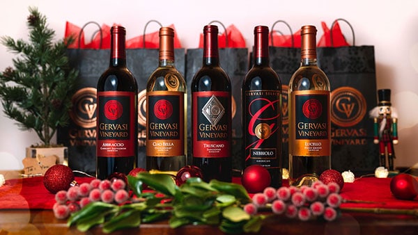A festive lineup of Gervasi Vineyard holiday wines displayed with seasonal decorations and gift bags, perfect for holiday gifting and wine lovers.