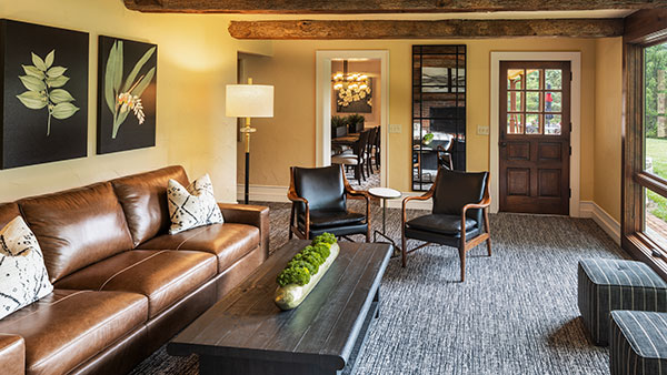 Spacious farmhouse-style living room at Gervasi Vineyard featuring a leather couch, wood-beam ceiling, and cozy rustic decor.