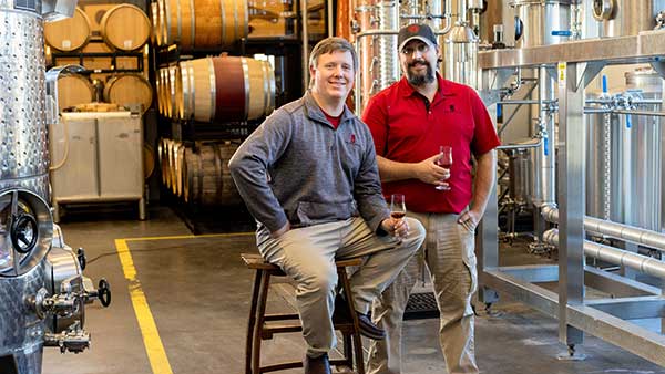 Gervasi Spirits distillers posing inside the distillery with barrels and stainless steel equipment