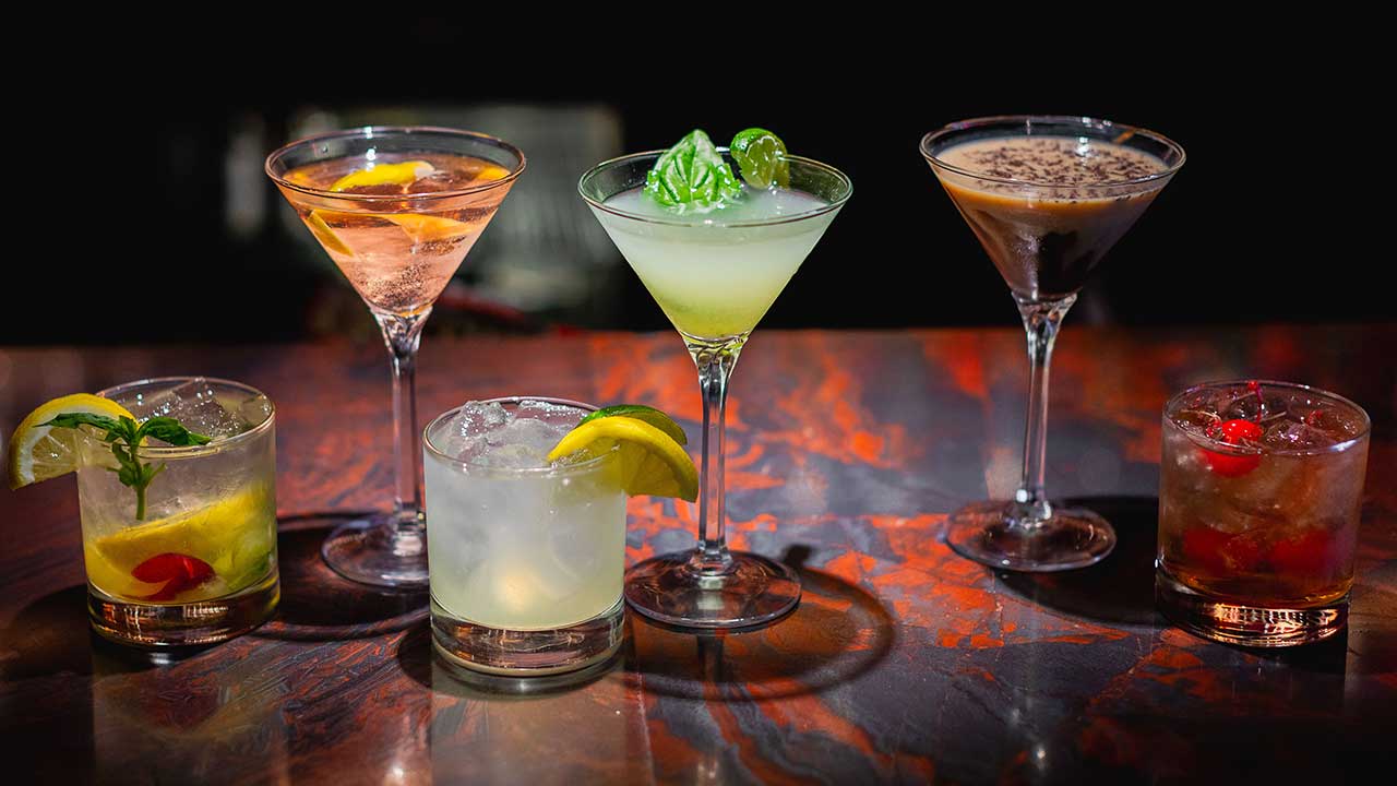 Six handcrafted cocktails on a dark marble bar at Gervasi Vineyard, showcasing creative martinis and mixed drinks with fresh citrus and herb garnishes.