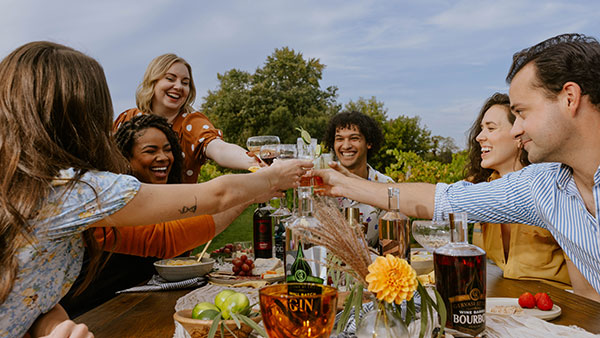 Group of friends toasting with Gervasi Spirits bourbon and gin at an outdoor vineyard celebration
