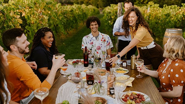 Friends dining among the vines at Gervasi Vineyard with wine, spirits, and artisanal dishes celebrating spring gatherings.