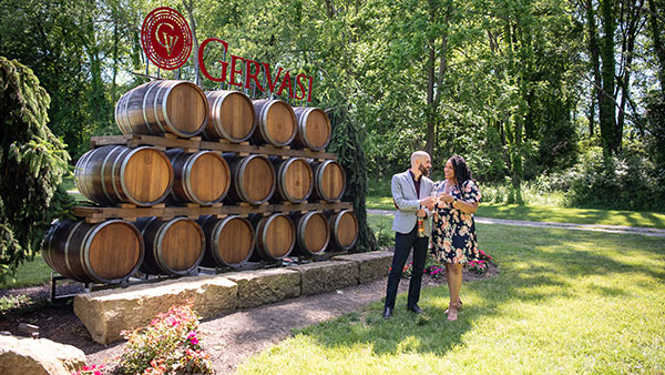 Couple enjoying a sunny afternoon beside the iconic stacked wine barrel display at Gervasi Vineyard in Canton, Ohio.