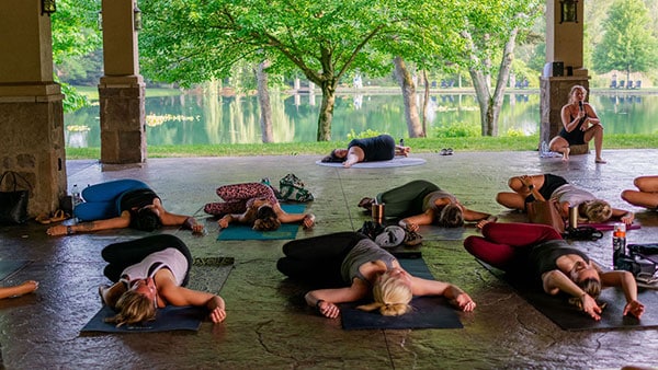 Group yoga session under the pavilion at Gervasi Vineyard overlooking the lake, part of the summer wellness series.